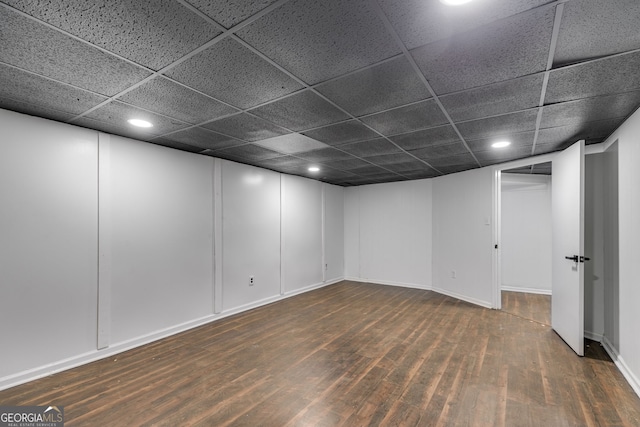 basement featuring a paneled ceiling and dark hardwood / wood-style flooring