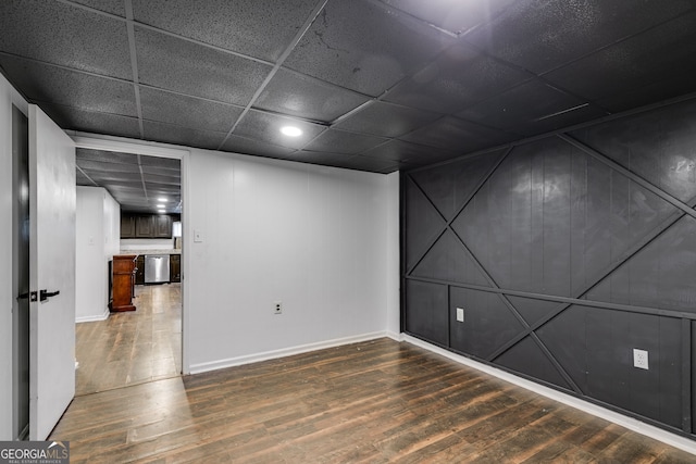 empty room with a paneled ceiling and dark wood-type flooring