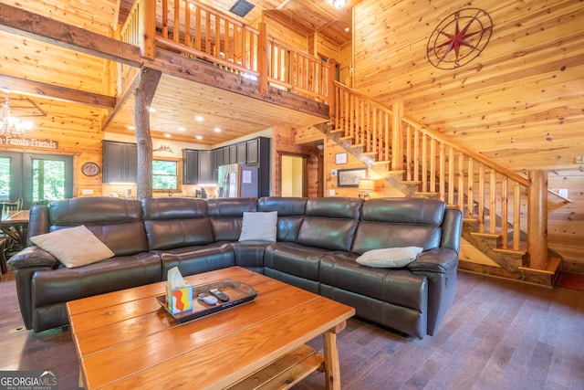 living room with dark hardwood / wood-style floors, wooden walls, and a high ceiling