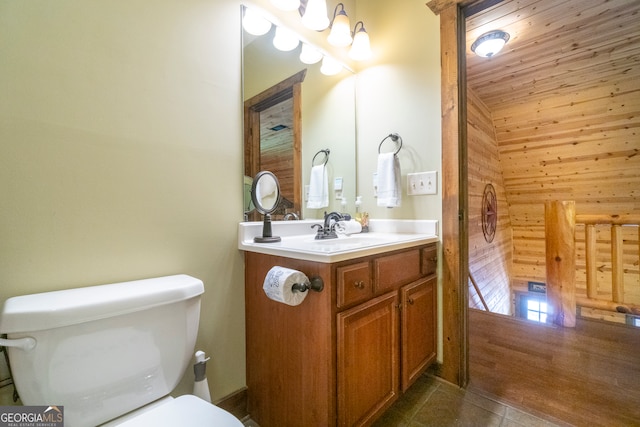 bathroom with vanity, toilet, wood walls, and tile patterned floors