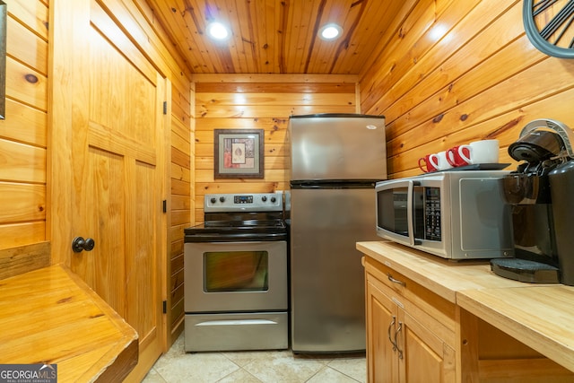 kitchen with wood ceiling, light tile patterned floors, appliances with stainless steel finishes, wood counters, and wooden walls