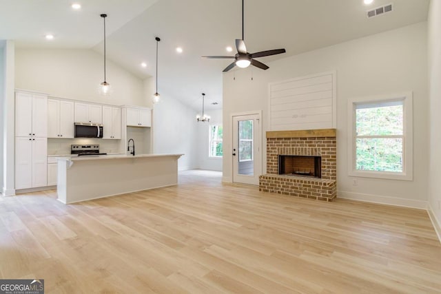 unfurnished living room with a wealth of natural light, light hardwood / wood-style flooring, and high vaulted ceiling