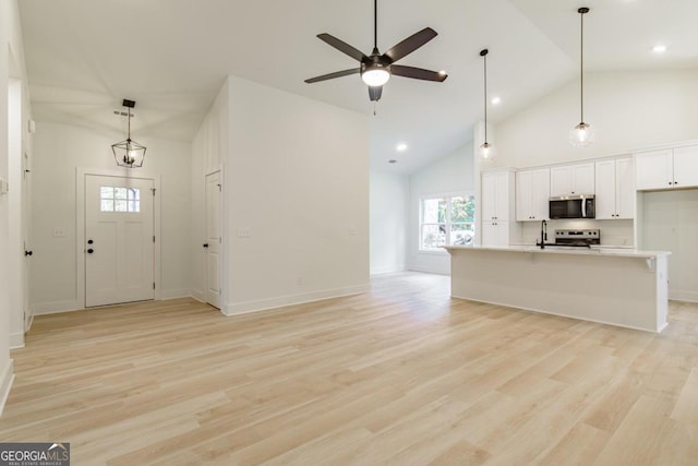 entryway with ceiling fan, high vaulted ceiling, and light wood-type flooring