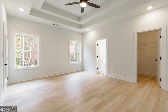 unfurnished bedroom with a spacious closet, ceiling fan, a closet, and multiple windows