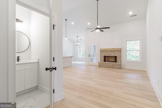 bathroom with vanity, a brick fireplace, plenty of natural light, and ceiling fan with notable chandelier