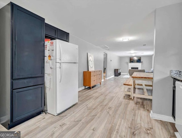 kitchen with blue cabinets, light hardwood / wood-style flooring, and white refrigerator