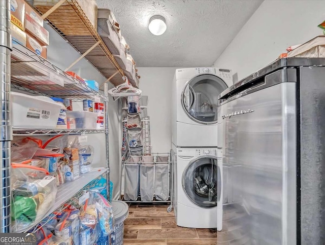 washroom with stacked washing maching and dryer, hardwood / wood-style flooring, and a textured ceiling