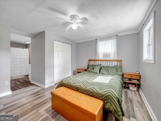 bedroom with a closet, ceiling fan, multiple windows, and hardwood / wood-style floors