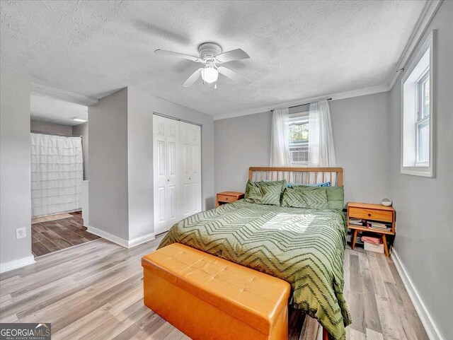 bedroom with ceiling fan, a textured ceiling, hardwood / wood-style flooring, ornamental molding, and a closet