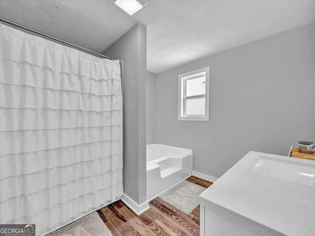 bathroom with vanity, a textured ceiling, plus walk in shower, and wood-type flooring