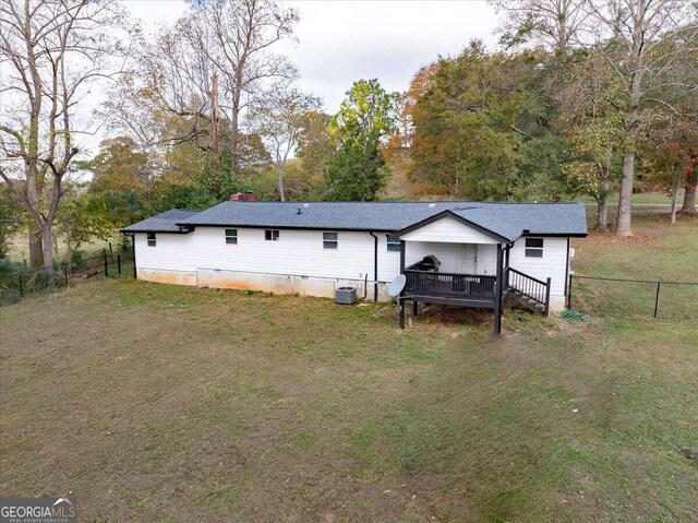 rear view of house with a wooden deck, central AC, and a lawn