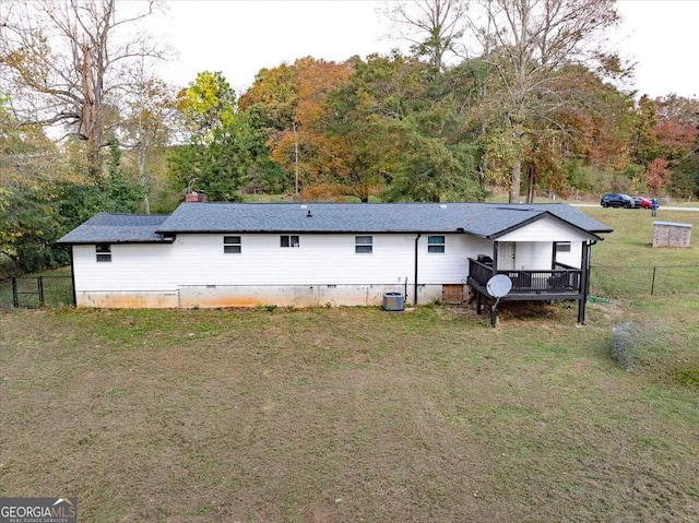 back of property with a wooden deck, cooling unit, and a lawn