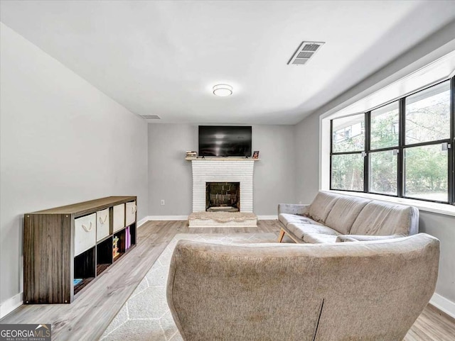 living room with light hardwood / wood-style floors and a brick fireplace