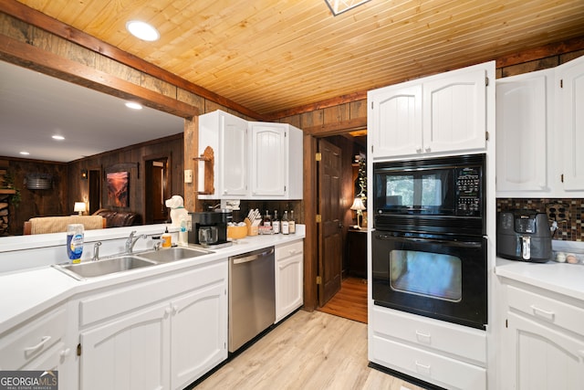 kitchen featuring white cabinetry, wood walls, black appliances, and sink