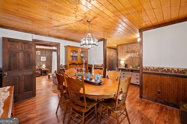 dining space with wood ceiling, wood walls, a chandelier, and hardwood / wood-style floors