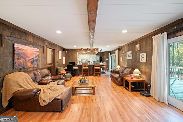 living room featuring light hardwood / wood-style floors, wood walls, and beamed ceiling