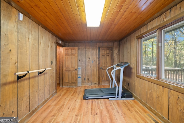 exercise area featuring wooden walls, light hardwood / wood-style flooring, and wooden ceiling