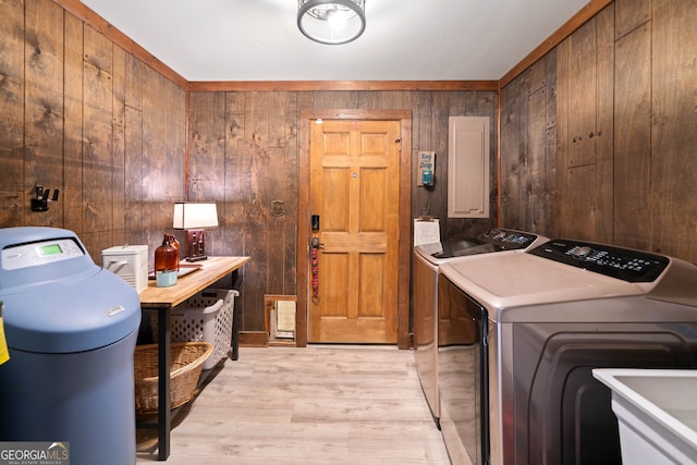 clothes washing area featuring light hardwood / wood-style flooring, sink, independent washer and dryer, wooden walls, and electric panel