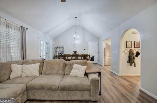 living room featuring a notable chandelier, hardwood / wood-style flooring, and lofted ceiling