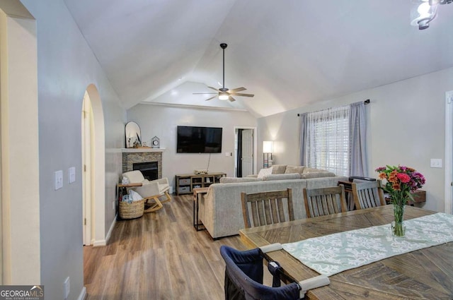 dining area featuring vaulted ceiling, a fireplace, light wood-type flooring, and ceiling fan