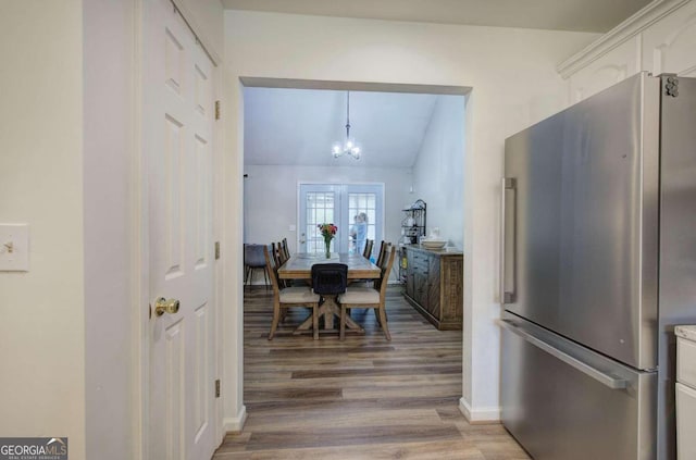 dining area with lofted ceiling, hardwood / wood-style flooring, and an inviting chandelier