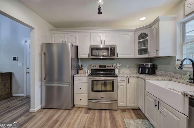 kitchen featuring appliances with stainless steel finishes, white cabinetry, and light hardwood / wood-style floors