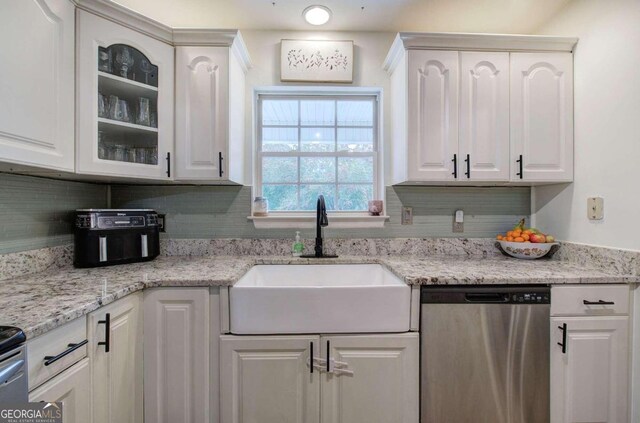 kitchen featuring decorative backsplash, white cabinets, stainless steel dishwasher, and sink