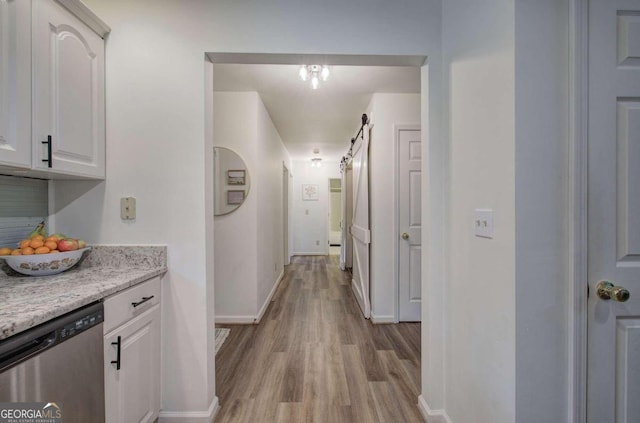 corridor featuring a barn door and light wood-type flooring