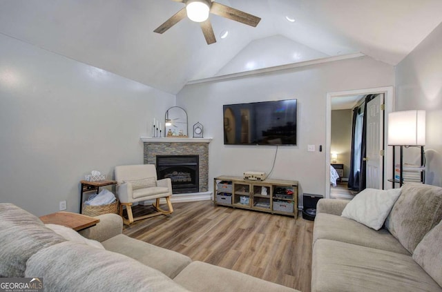 living room with light hardwood / wood-style floors, lofted ceiling, a fireplace, and ceiling fan