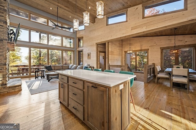 kitchen with light wood-type flooring, decorative light fixtures, high vaulted ceiling, and a skylight