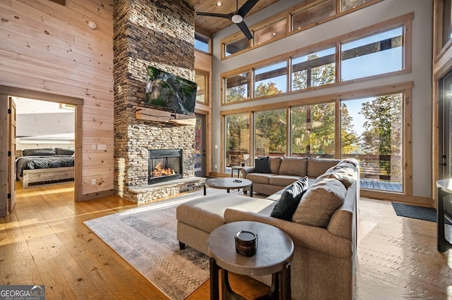 living room featuring a stone fireplace, a high ceiling, and light wood-type flooring