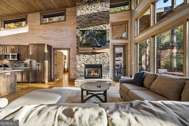 living room featuring wooden walls, light hardwood / wood-style floors, high vaulted ceiling, and plenty of natural light