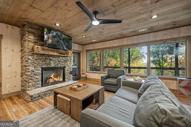 living room featuring wooden walls, a fireplace, hardwood / wood-style flooring, and wooden ceiling