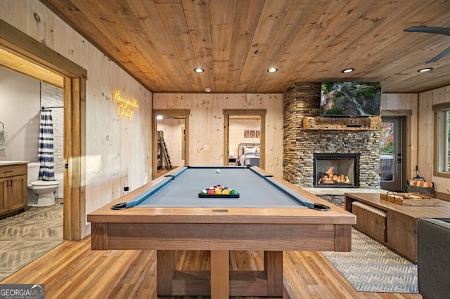 game room with a fireplace, wood walls, wooden ceiling, and light wood-type flooring