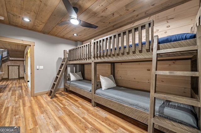 unfurnished bedroom with ceiling fan, wood ceiling, wood walls, and hardwood / wood-style floors