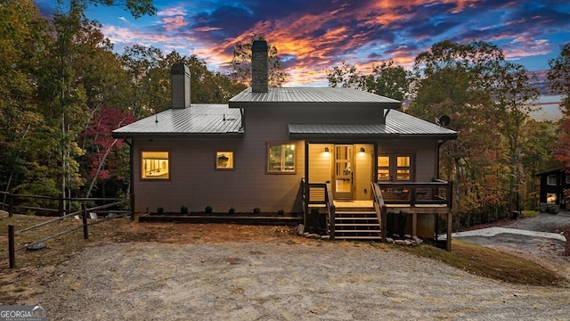 back house at dusk featuring covered porch