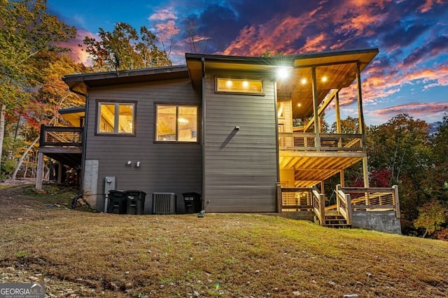 back house at dusk with a yard and a wooden deck