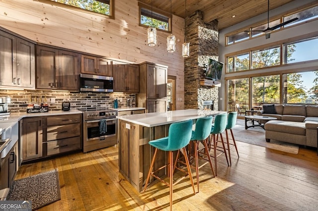 kitchen featuring a kitchen breakfast bar, light hardwood / wood-style flooring, stainless steel appliances, and a high ceiling