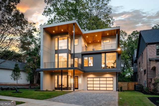 contemporary house featuring a garage, cooling unit, a lawn, and a balcony