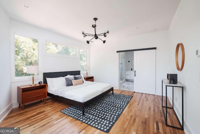 bedroom with connected bathroom, an inviting chandelier, and light hardwood / wood-style floors