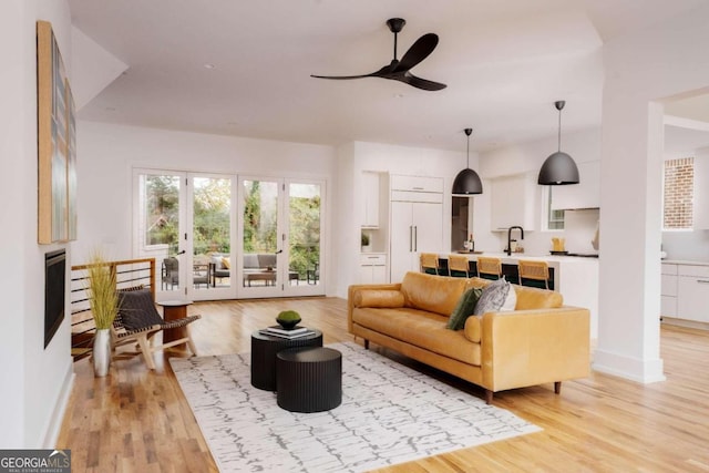 living room with french doors, light wood-type flooring, ceiling fan, and sink