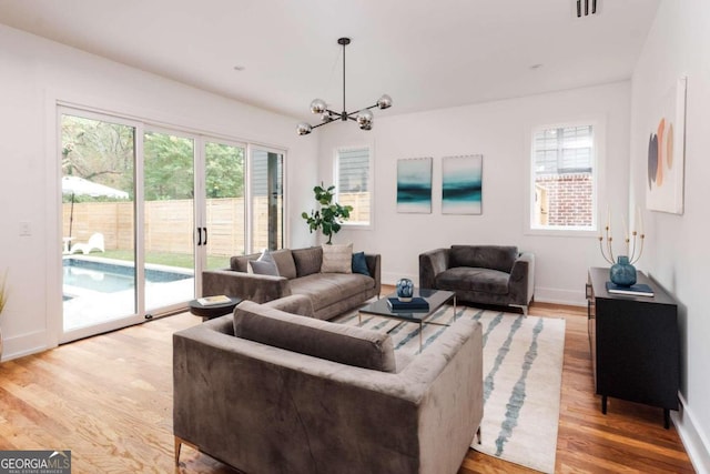 1281 Avalon Pl NE, Atlanta, GA 30306 - living room featuring a chandelier, light wood-style flooring, and baseboards