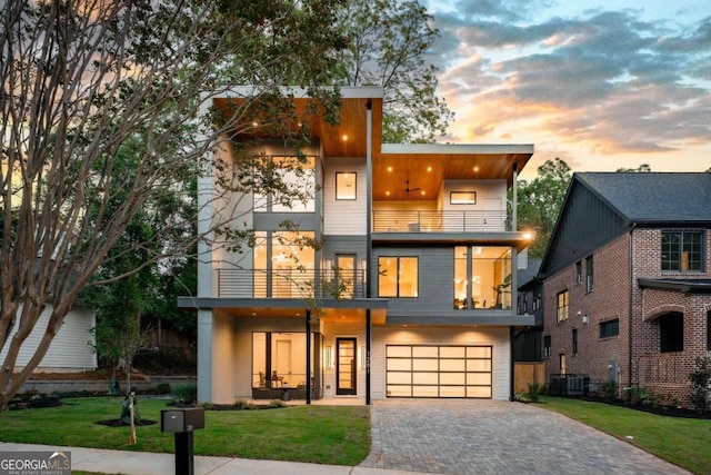 contemporary home with a garage, cooling unit, a balcony, and a yard