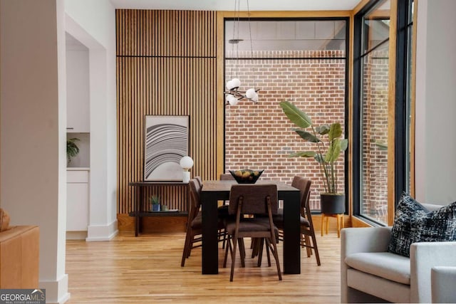 dining room featuring light wood-type flooring and brick wall