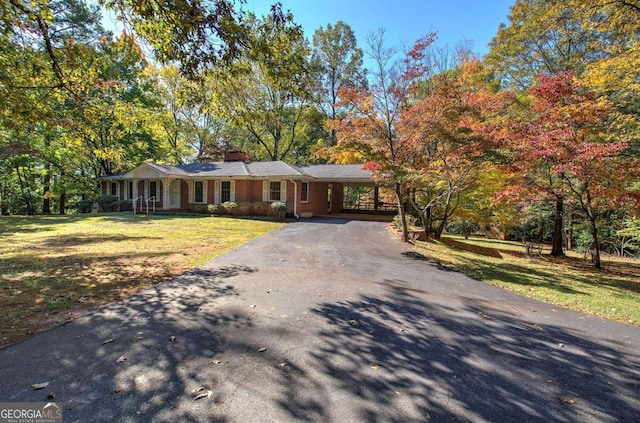 ranch-style house featuring brick siding, driveway, a front lawn, and an attached carport