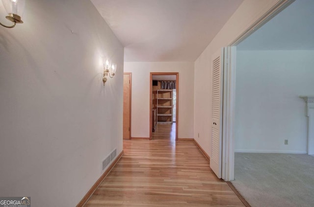 hall featuring light wood finished floors, visible vents, and baseboards