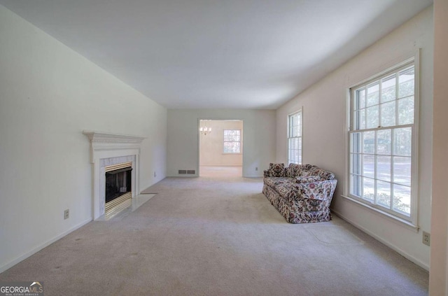 unfurnished living room featuring carpet floors, an inviting chandelier, a premium fireplace, and baseboards