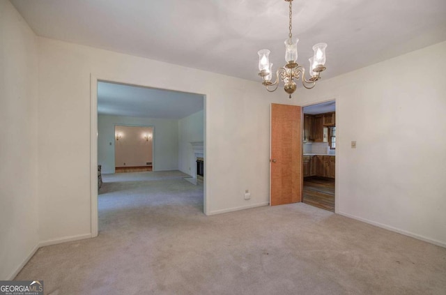 unfurnished dining area featuring baseboards, carpet, a fireplace, and a notable chandelier