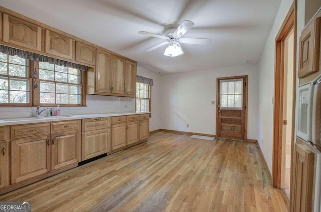 kitchen featuring light wood finished floors, light countertops, and a sink