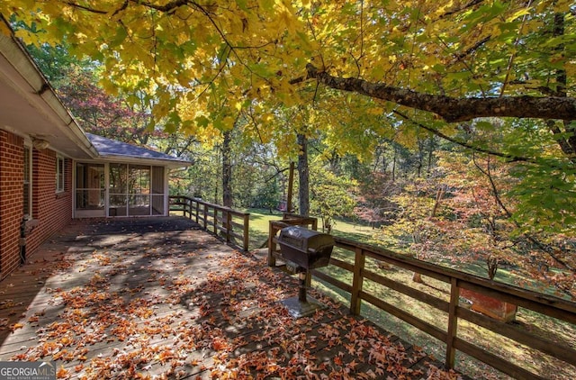 wooden deck featuring a sunroom and area for grilling